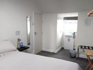 1 dormitorio con cama blanca y lavamanos en Comfort Guest House en Leicester