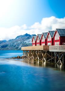 a row of red houses on a dock in the water at Lofoten Rorbu Lodge in Offersøya