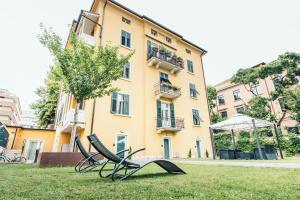 a group of chairs sitting in the grass in front of a building at ALPENCITY SUITES in Trento