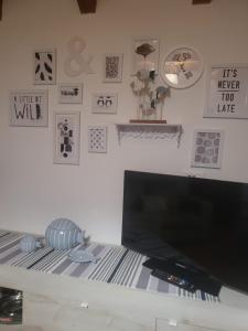 a room with a tv and a wall with pictures at A casa di Anna in Galtellì