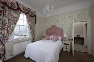 a bedroom with a bed with a pink headboard and a window at Willoughby Place in Enniskillen
