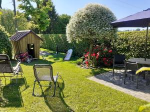 un jardín con sillas, una mesa y una casa para perros en l'Heure bleue, en Aywaille