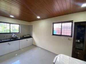 a kitchen with white cabinets and two windows at Farmhouse in Pune city in Pune