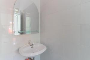bagno bianco con lavandino e specchio di KoolKost @ Ikost Cimahpar Indah a Bogor