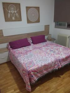 1 dormitorio con 1 cama grande con almohadas moradas en Apartamento Poniente con dos baños centrico, en Logroño