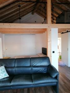 a black leather couch in a room with a bed at A Casinha in Caldas da Rainha