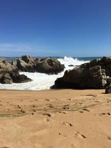 a sandy beach with rocks and the ocean at Cabañas en Algarrobo Norte in Algarrobo