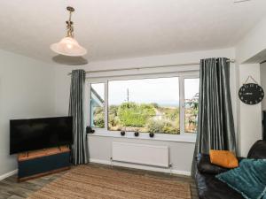 a living room with a couch and a large window at Honeycroft in Boscastle