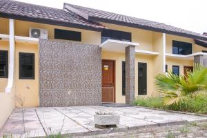 a yellow house with a door and a courtyard at OYO 3438 Pasir Padi Inn Syariah in Kebinti