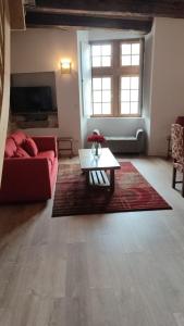 Salardine Apartments - Duplex with Modern Touch في Châlus: غرفة معيشة مع أريكة حمراء وطاولة قهوة