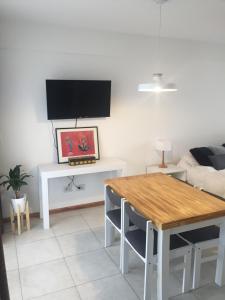 uma sala de estar com uma mesa e uma televisão na parede em Monoambiente Céntrico único em Puerto Madryn