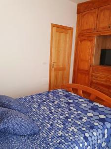 a bedroom with a blue and white bed with a wooden cabinet at V.V JUANA in Valverde