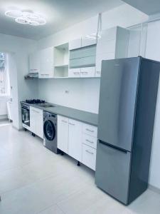 a kitchen with a refrigerator and a washer and dryer at Oble Apartament's center in Craiova
