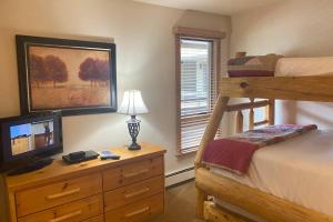 a bedroom with a bunk bed and a desk with a television at Cozy Apartment, Right in front of Lionshead Gondola in Vail +25 photos