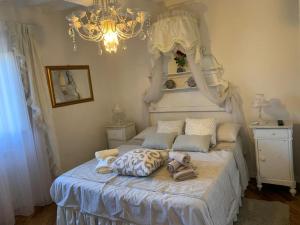 una camera da letto con letto bianco, cuscini e lampadario a braccio di Appartamento incantevole nel centro di Arezzo ad Arezzo