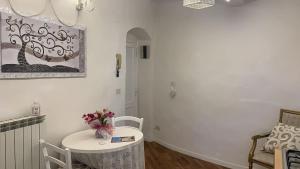 biały pokój ze stołem i wazonem kwiatów w obiekcie Appartamento incantevole nel centro di Arezzo w Arezzo