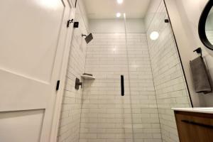 y baño con ducha y pared de azulejos blancos. en The Queen Suite at Prince Street Inn, en Alexandria