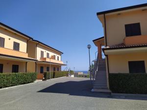 a building with a staircase next to a building with the ocean at Appartamento Villaggio Emerald in Mandatoriccio