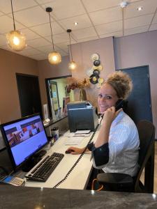 een vrouw die aan een bureau met een computer aan het bellen is bij Hotel Restaurant Talens Coevorden in Coevorden