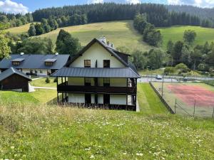 a house on top of a hill with a field at Apartmány NETA Velké Karlovice, Polanský Dvůr in Velké Karlovice