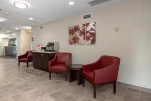 a waiting room with red chairs and a counter at Red Roof Inn PLUS+ Jacksonville – Southpoint in Jacksonville