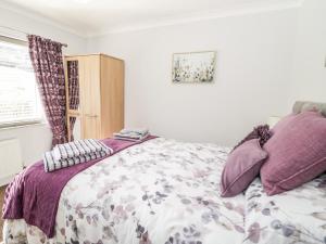 um quarto com uma cama com almofadas roxas em The Nook 285B em Colwyn Bay