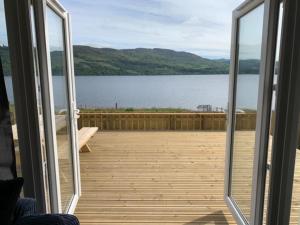 a sliding glass door with a view of a lake at Loch Ness Cottage in Fort Augustus