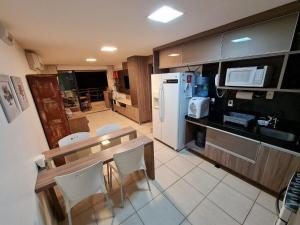 een keuken met een tafel en een witte koelkast bij Apartamento mobiliado Beach Place Porto das Dunas in Prainha