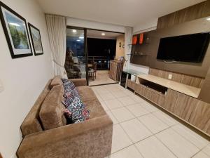 a living room with a couch and a flat screen tv at Apartamento mobiliado Beach Place Porto das Dunas in Prainha