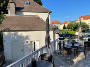 einen Balkon mit Tischen, Stühlen und einem Sonnenschirm in der Unterkunft Villa Antonia in Bautzen