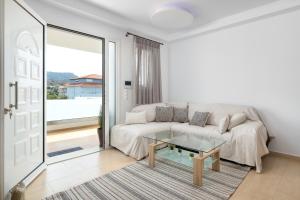 uma sala de estar branca com um sofá e uma mesa de vidro em White House Kokas Luxury Apartments em Kremasti