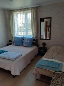 a bedroom with two beds with blue pillows and a window at Гостевой дом Уют in Karolino-Buhaz