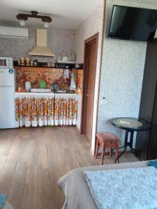 a room with a kitchen with a table and a tv at Гостевой дом Уют in Karolino-Buhaz