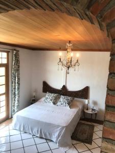 a bedroom with a large white bed with a chandelier at Morada Campestre a 45 minutos de Madrid in Chozas de Canales