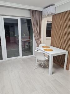 uma sala de jantar branca com uma mesa e cadeiras brancas em Modern Studio em Oradea