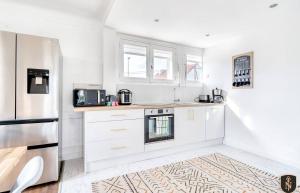 uma cozinha com armários brancos e um frigorífico em Grande maison 160 m2 6 chambres à Caen em Caen