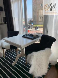 une table et des chaises blanches avec une grande fenêtre dans l'établissement El Sol Zandvoort 2, à Zandvoort