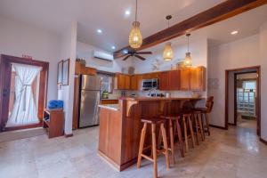 uma cozinha com armários de madeira e um bar com bancos em Indigo Belize 2B Condo em San Pedro