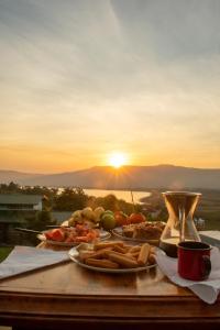 uma mesa coberta com pratos de comida com o pôr-do-sol ao fundo em Chalé da Ferrugem em Garopaba