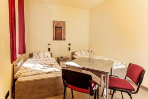 a room with two beds and a table and chairs at Hotel und Hostel Gleisbett in Annaberg-Buchholz