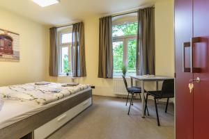 een slaapkamer met een bed en een tafel en stoelen bij Hotel und Hostel Gleisbett in Annaberg-Buchholz
