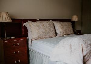 a bed with two pillows and a nightstand with two lamps at Hollyburn in Crulivig