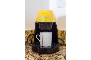 a coffee maker with a cup on a counter at Flat 1506 - Studio duplo em Macaé in Macaé