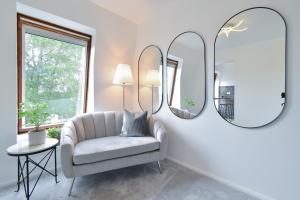 a living room with a chair and two mirrors at Stylish One Bed Apartment Near Cotswolds RAF in Carterton