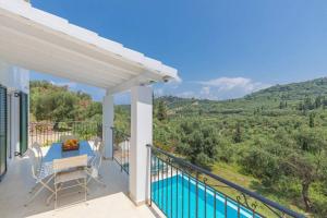 a balcony with a table and chairs and a swimming pool at Villa Eleonas in Strongylí
