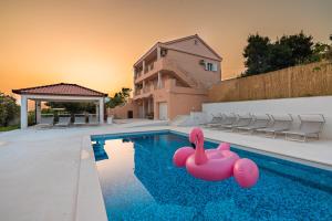 a swimming pool with two pink inflatable flamingos in the water at Villa Summer in Rtina
