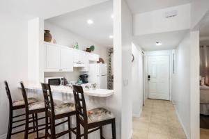 a kitchen with white cabinets and a bar with chairs at Royal Palm 203 in Marco Island +19 photos