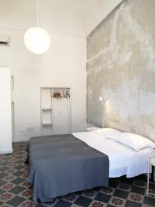 1 dormitorio con 1 cama y una pared grande en Antico Mercato Ortigia Apartment en Siracusa