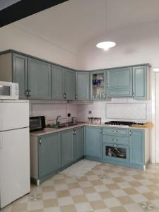 cocina con armarios azules y nevera blanca en Antico Mercato Ortigia Apartment, en Siracusa
