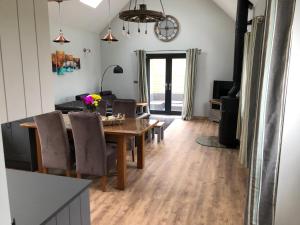 a dining room and living room with a table and chairs at Newly Converted Luxury Barn With Private Hot Tub in Bodfari